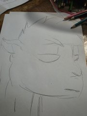 A simple pencil sketch of an anime-style character's face on white paper, with colored pencils visible at the edge.