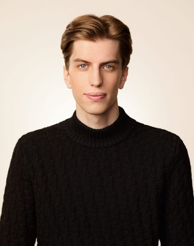 A young man with light brown hair, blue eyes, and a black cable-knit turtleneck sweater poses against a plain white backdrop. The post suggests the image likely represents "Leopold," the trader referenced in the caption, who is reportedly returning to AI call options following a margin call, just as stocks like AMD and BE are experiencing sharp declines of 5.7% and 7.3% respectively.