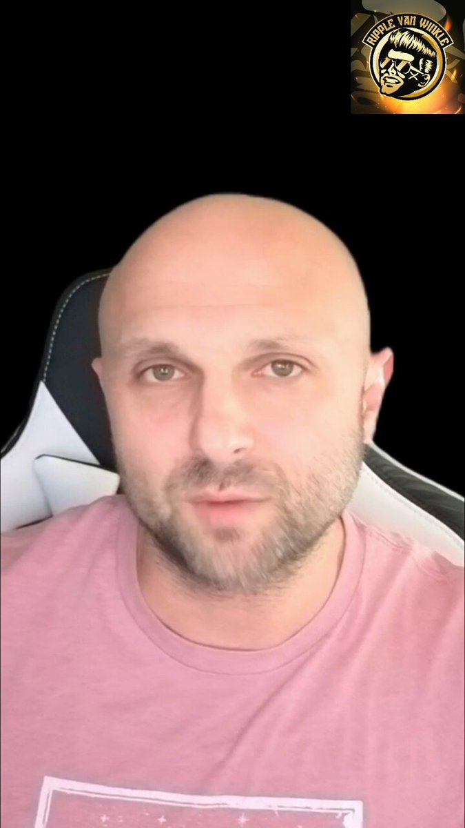 The image features a bald man wearing a pink shirt, sitting in a chair with a serious expression as he looks directly at the camera. The background of the photo is black, which contrasts with the white wall behind him. There are two logos present in the image - one on the right side and another on the left side. The text "BREAKING: Trump just told America that Bitcoin will overtake gold while he waits for the CLARITY Act to hit his desk" suggests a connection between the man's serious expression, the digital transformation of money, and the recent events in politics.