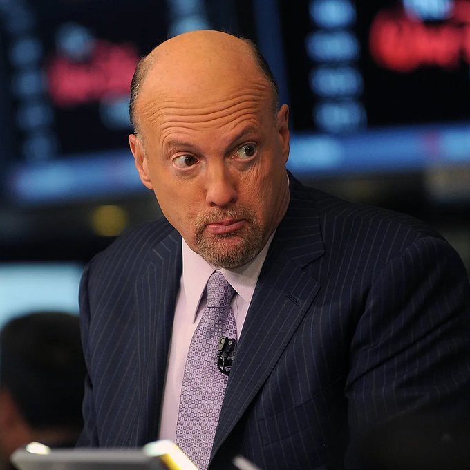 Jim Cramer, wearing a pinstripe suit and purple patterned tie, appears on CNBC with a skeptical expression, ironically staring back at viewers after his Bitcoin "buy" recommendation caused a $2,000 crash and $108 billion market wipeout.