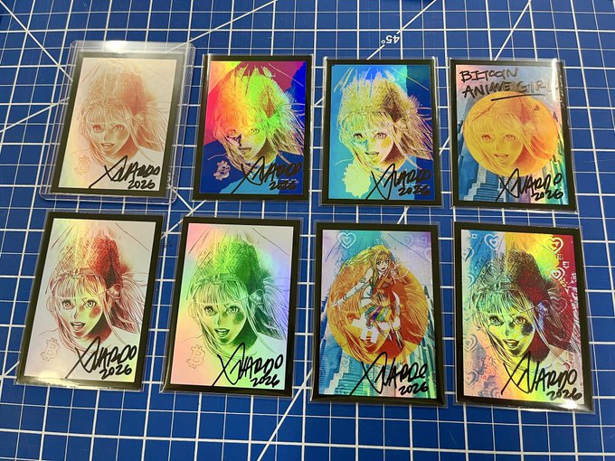 Eight hand-drawn anime-style holographic stickers of female characters with rainbow prismatic effects, signed and dated 'XIIANNO 2026', displayed on a blue cutting mat, with one labeled 'BETWEEN ANIMEGIRL'.
