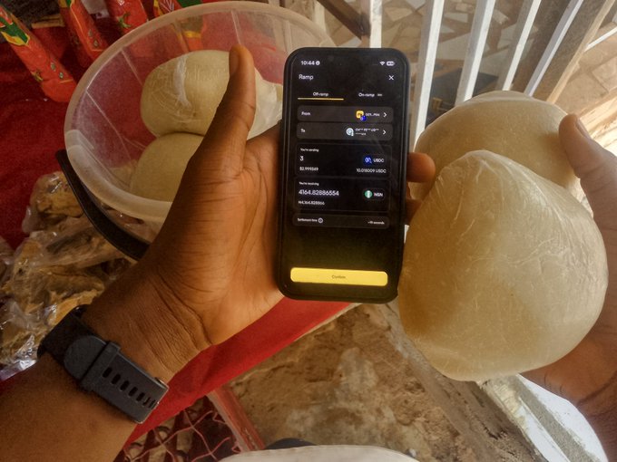 A person holding a smartphone displaying a Ramp crypto on-ramp transaction alongside a large piece of dough or pastry.