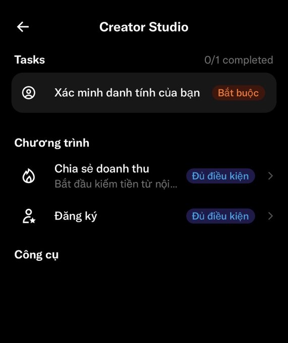 A Vietnamese-language Creator Studio settings screen in dark mode showing 0/1 tasks completed, with required identity verification ('Xác minh danh tính của bạn') and sufficient conditions ('Đủ điều kiện') for revenue sharing and registration programs.