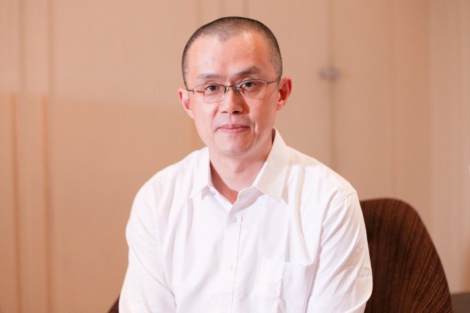 The image shows a man wearing glasses sitting down, possibly in an office setting or at home. He has short hair and is looking directly at the camera with a serious expression. The background appears to be a plain wall, which contrasts with his focused demeanor. There are no other people visible in the photo, making him the main subject of attention.