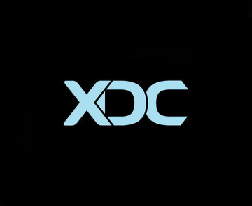 The image displays the "XDC" logo in light blue text on a black background, representing XDC Network as mentioned in the announcement of its new integration with Bridge for stablecoin settlement and fiat ramp services.
