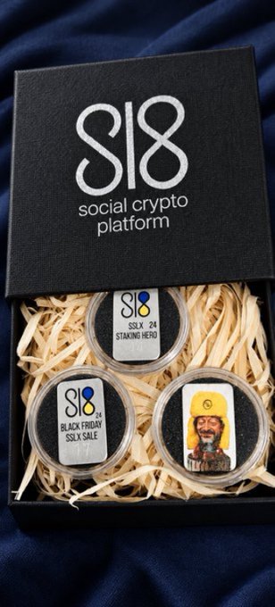 A black gift box from the "social crypto platform SL8" contains three silver coins nestled in wood shavings, labeled "SSLX 24 STAKING HERO," "BLACK FRIDAY SSLX SALE," and one featuring an illustrated bearded man in traditional attire. The display visually represents the SL8 staking campaign highlighted in the post, which promotes tiered APY rewards (28%–62%) and bonuses like tokenized Ukrainian gold and silver commemorative coins.