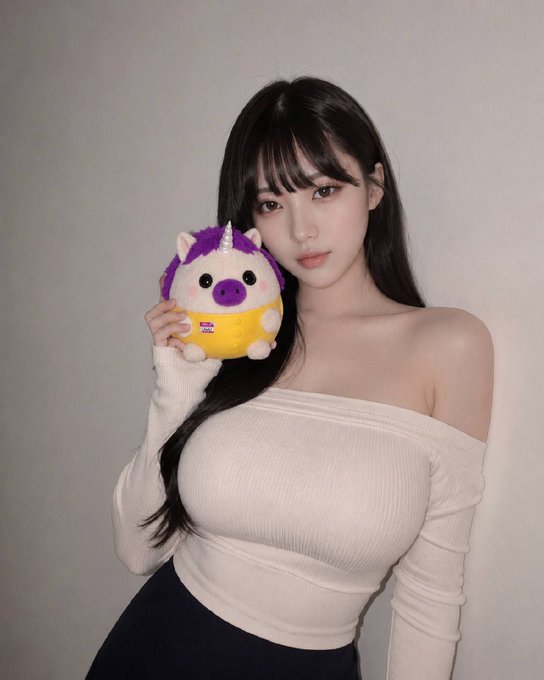 A young woman with long dark hair holds a purple and yellow unicorn plush toy near her face while wearing an off-shoulder beige top, visually tying into the post's reference to "ladies love Unicorns" and the $UwU crypto token.