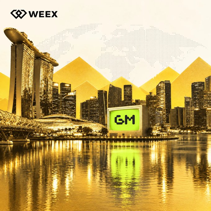 A golden-hued city skyline features the iconic "GM" logo displayed on a glowing billboard, with the WEEX logo in the corner, visually highlighting the ticker in the context of an upcoming market movement.