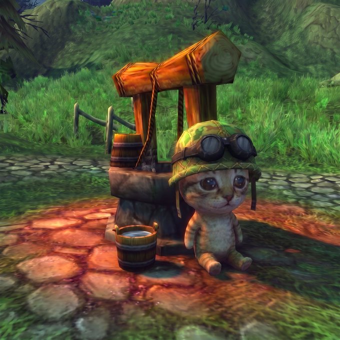 A 3D-rendered cartoon kitten wearing an aviator helmet with goggles sits next to a small wooden wishing well with buckets in a lush green grassy environment.