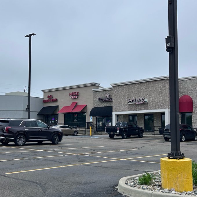 iced coffee shop with red awning and "WOW" sign, black SUV parked outside, gray building with white trim, and yellow pole on the side of the road.