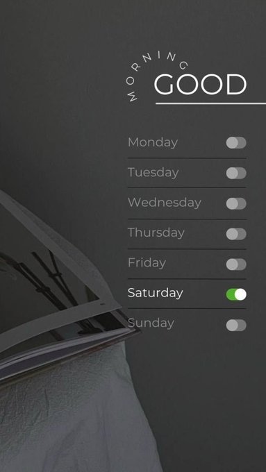 A mobile app interface titled 'MORNING GOOD' with toggle switches for each day of the week, with Saturday toggled on (green) and the others off, displayed over a background image of a book.
