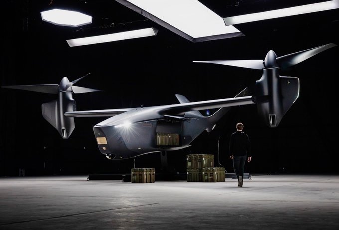 The image shows a sleek, dark military-style tiltrotor aircraft on display in a hangar, with a person walking nearby and cargo crates stacked below, suggesting a partnership unveiling. It illustrates the context of the post about Archer Aviation ($ACHR) manufacturing the core platform (Halo) that Anduril will equip into the lethal "Thunder" variant for military and corporate use.