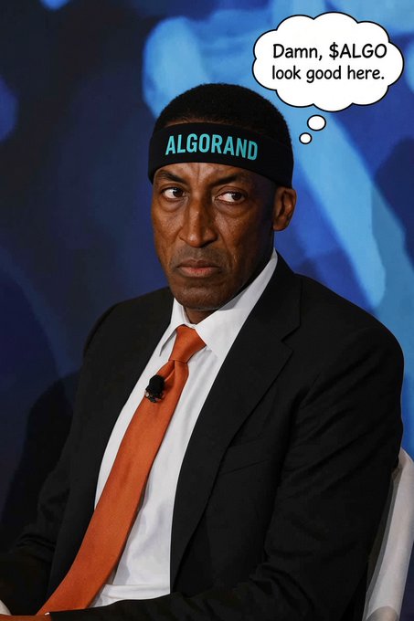 A man in a suit and orange tie wears a black headband with the text 'ALGORAND' in blue, accompanied by a thought bubble reading 'Damn, $ALGO look good here.'