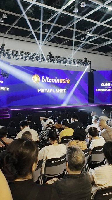 Audience seated in chairs labeled 'METAPLANET' watching a stage with screens displaying 'bitcoinasia' and 'METAPLANET PRESENTED BY' at a Bitcoin Asia conference event.