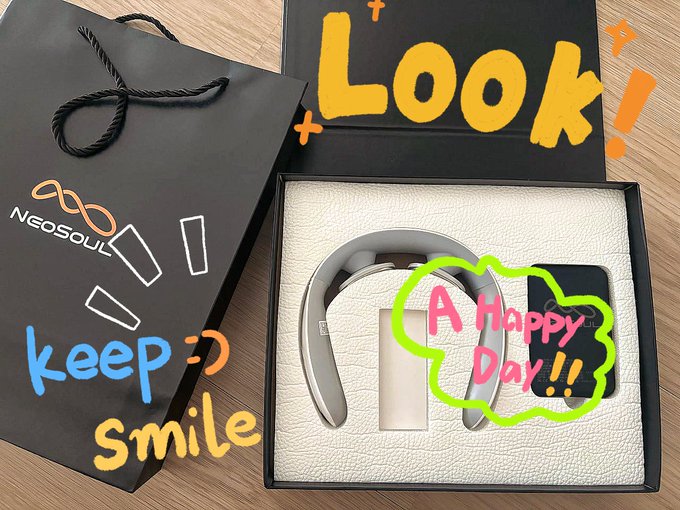An unboxed pair of silver headphones from a black NeoSOUL 'Keep Smile' gift bag, decorated with text reading 'Look!' and 'A Happy Day!!!'.