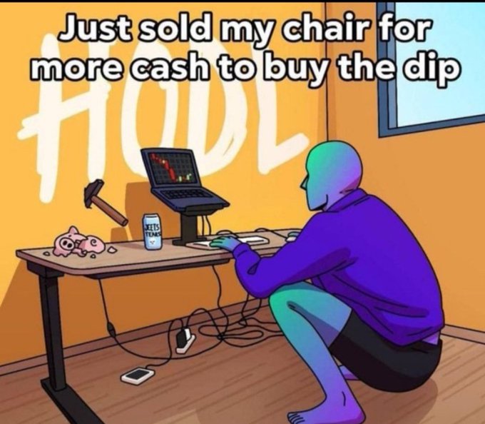 A hooded figure sits on a makeshift seat (a plastic bin) at a desk with a laptop, checking charts while surrounded by scattered objects including a piggy bank and cash. The caption reads "Everything is flying right now. Looks like the market is finally waking up. We're so back." The image humorously suggests someone so committed to riding the market rally that they've literally sold off their furniture for extra capital to invest.