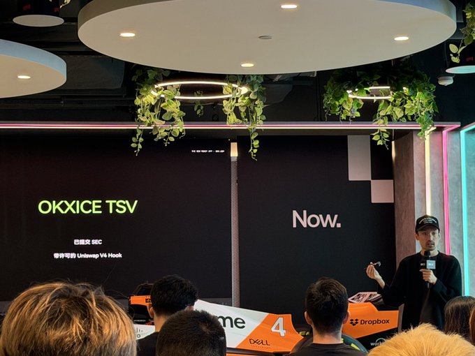 A presenter speaks at a conference while a screen displays "OKXICE TSV" and "Now." alongside logos for Dropbox and OKX, aligning with a post summarizing @zakk_okx's talk about X Layer developments covering X money, RWA, meme, exchange OS, and OKXICE TVS.