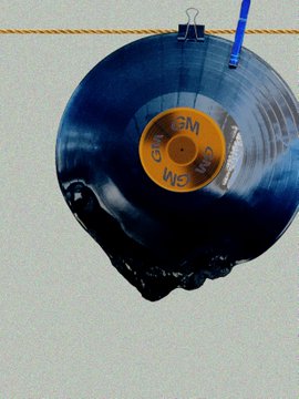 The image features a blue vinyl record with an orange label, hanging from a rope or string. The record appears to be slightly damaged, possibly due to being exposed to sunlight for some time. The background of the image is white, which contrasts with the vibrant colors of the record and its label. There are no other objects in the image besides the record itself.