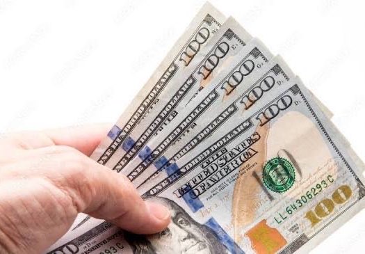 A hand holding a fan of US one-hundred-dollar bills against a white background.