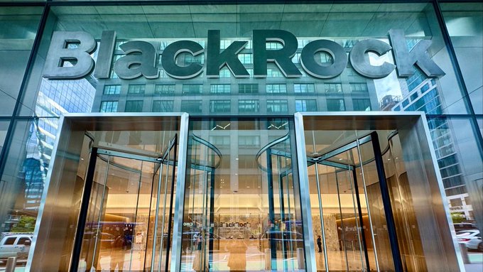 The glass entrance doors of the BlackRock office building with the company name displayed in large metallic letters above the revolving doors.