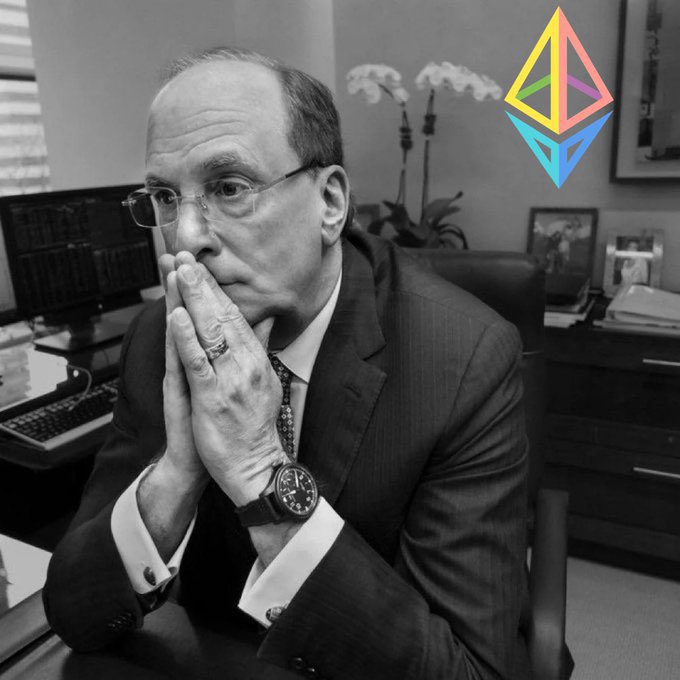 A black-and-white photo of a man in a suit with glasses, resting his chin on his clasped hands, with a colorful Ethereum logo superimposed in the top right corner.
