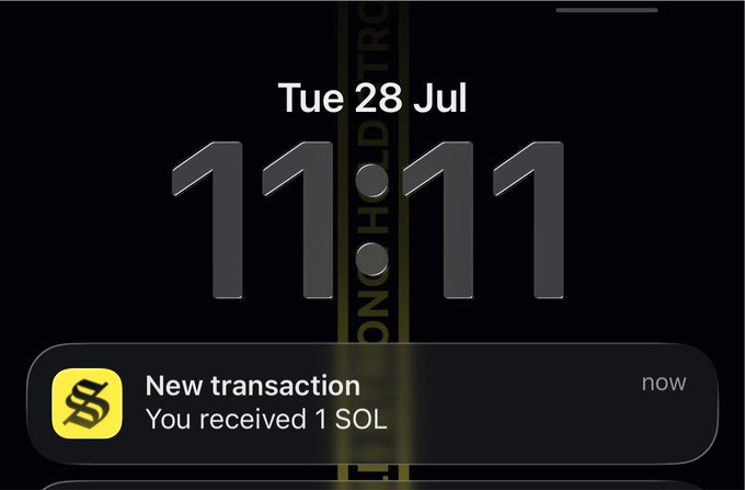 An iPhone lock screen displays the time 11:11 on Tuesday, July 28, alongside a notification reading "New transaction: You received 1 SOL," tying perfectly to the post's caption about making a wish at 11:11 with a single Solana.
