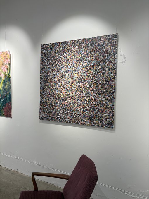 An art gallery displaying a pixelated photo mosaic artwork on a white wall.