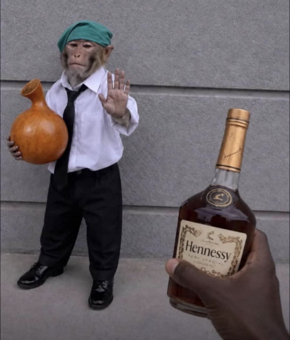 A monkey dressed in a green beret, white shirt, black tie, and pants holds a brown jug while holding up a hand in refusal toward a bottle of Hennessy Very Special Cognac being offered. The image humorously suggests rejecting alcohol for a sober, wholesome weekend morning.