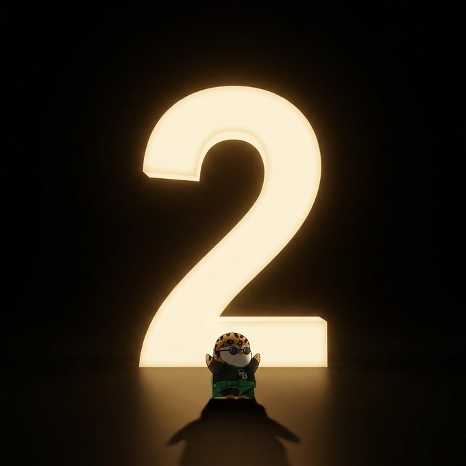 A small plush toy wearing a leopard-print hat and glasses sits in front of a large glowing white "2" numeral against a dark background.