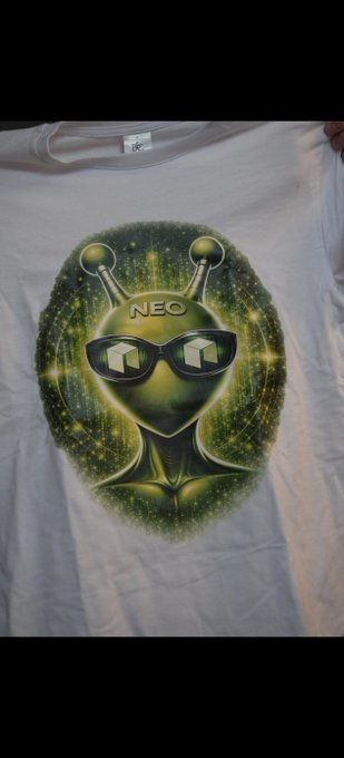 The image features a white t-shirt with an alien design on it, wearing glasses and sunglasses. The text "The Alien NEO T-Shirt" is written above the alien's head, indicating that this is a new collection of shirts from the company NeoUltimateShop. The design includes a green alien face with two horns and a pair of glasses, giving it a unique and futuristic appearance.