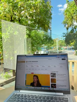 The image shows a laptop computer sitting open with an internet browser window displaying a news website, possibly from the US Stock or AI stock. The background of the image features trees outside a building, suggesting that the setting might be an outdoor area like a patio or a balcony.