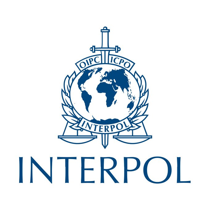 The official blue and white Interpol logo featuring a globe flanked by scales and a sword, with the text 'OIPC ICPO' and 'INTERPOL' displayed.