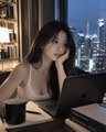 A young woman rests her head on her hand in front of a laptop in a dimly lit high-rise apartment overlooking a nighttime cityscape, capturing the tired late-night vigil of someone watching the markets when they should be sleeping. The moody, quiet scene perfectly complements the post's plea for relief from a restless crypto trader keeping watch against an unpredictable "whale."