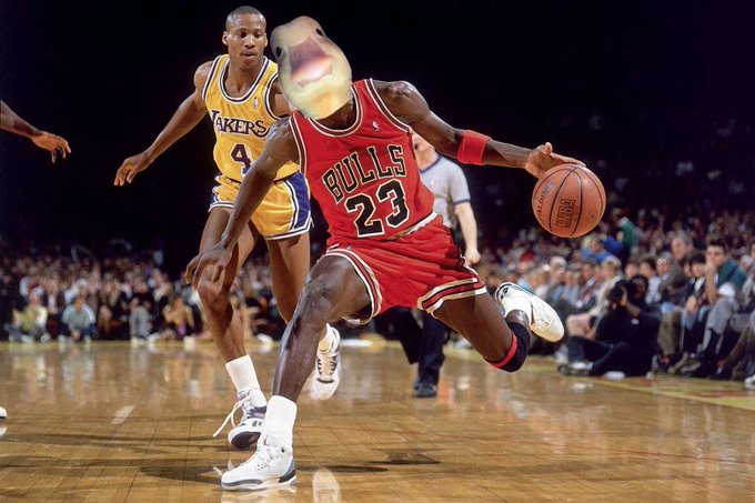 An action shot from a basketball game shows Michael Jordan in a red Chicago Bulls '23' jersey driving with the ball, while a player in a yellow Lakers jersey defends.