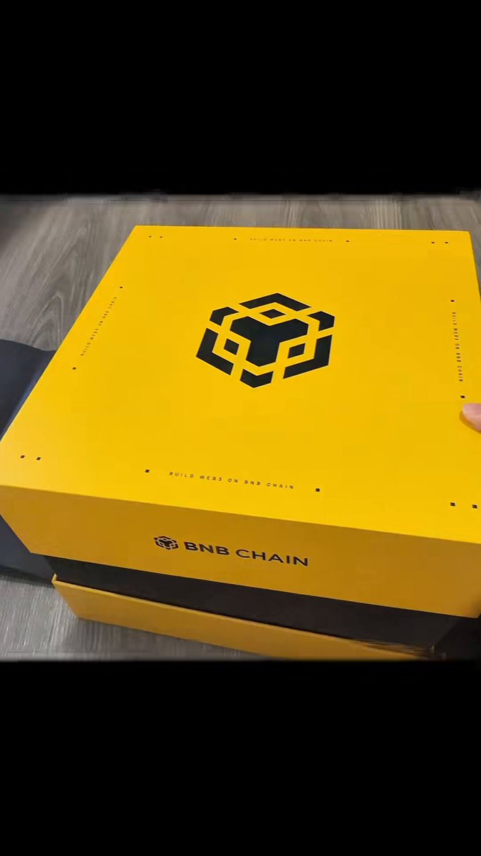 The image features a yellow box with black text, which reads "收到bnb chain's new release chain". The box has a logo of a cube on its side. It appears that someone has taken a photo of this item, possibly for sharing or promoting it.