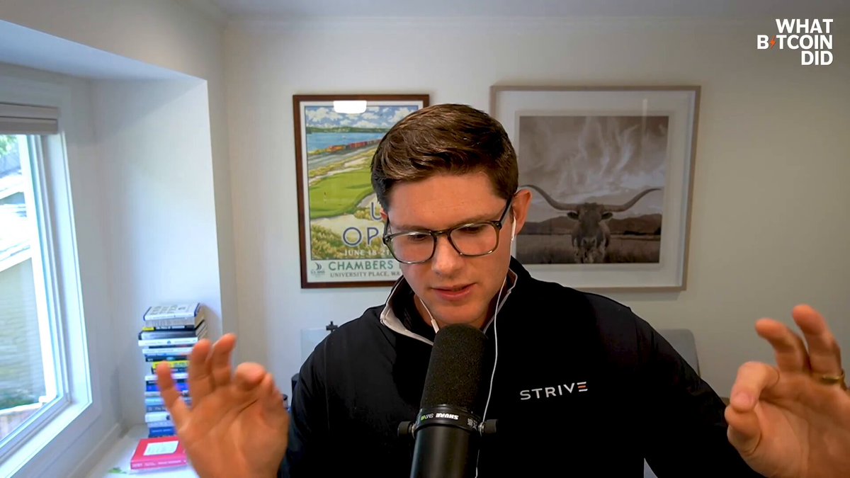The image shows a man wearing glasses seated behind a microphone, possibly at an event or live broadcast. He appears to be speaking into the microphone with his hands up as if he's emphasizing a point during his speech. In the background, there is a window that provides some natural light to the room. A poster and multiple books are also present in the space.
 
The image features text elements related to investing, including terms such as "High Yield", "Low Volatility", and "High Liquidity" which likely describe different investment opportunities or strategies. The presence of these descriptions suggests that this discussion may be about financial matters or related to the stock market in some capacity.