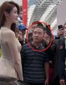A small blurry photo showing a man circled in red in a crowd, with a person dressed as a statue or mannequin visible to the left.