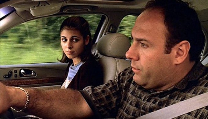 A man and a young woman are shown inside a car, with the man driving while wearing a plaid shirt and seatbelt, and the woman in the passenger seat looking toward him with a concerned expression, fitting the post's caption "Dad, are you bearish again?" as it suggests a serious or downbeat conversation between them.
