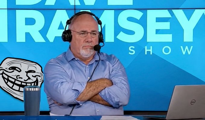 A man wearing headphones and a light blue shirt sits with arms crossed in front of 'THE DAVE RAMSEY SHOW' backdrop, with a laptop and tumbler visible on the desk.