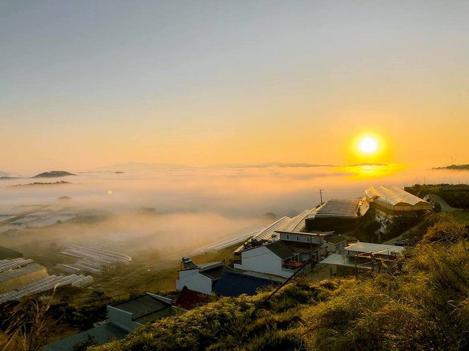 The image shows a beautiful sunrise over a foggy landscape. The sun is rising behind the fog, creating an atmospheric scene that captures the essence of a new day. In the background, there are several buildings situated at the base of a hill, adding depth to the image and emphasizing the vastness of the surrounding area. The post about CNPY Network discusses the benefits of using CNPY as a framework for launching sovereign appchains, which can be related to this serene landscape by highlighting how CNPY helps in creating a secure and efficient environment for developers to build their applications.