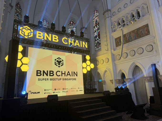 A large illuminated stage display for 'BNB CHAIN SUPER MEETUP SINGAPORE' set inside a church with stained glass windows.