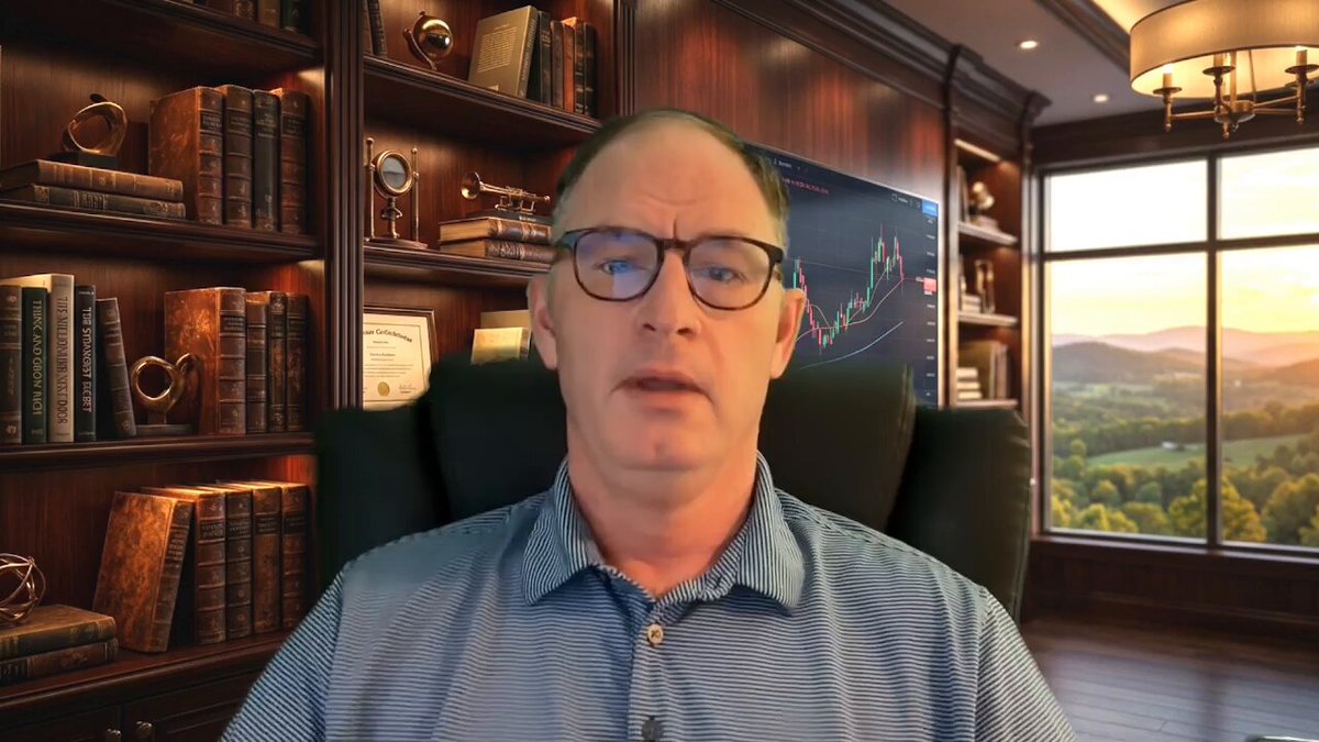 urn of gold coins sitting on a bookshelf with a window behind them, and a man wearing glasses seated at a desk looking directly at the camera.