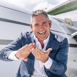 Grant Cardone smiles broadly while gesturing in front of a private jet, projecting the celebratory tone of Cardone Capital's latest acquisition of 10.5 BTC, which brings its holdings to over 2,700 BTC.