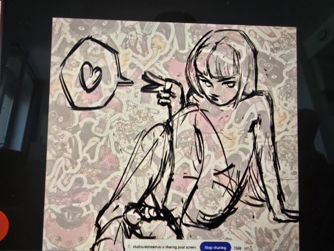 A digital sketch displayed on a screen showing a girl sitting with a speech bubble containing a heart, with a small UI bar at the bottom reading 'Stop sharing' and a StudioVE stream link.
