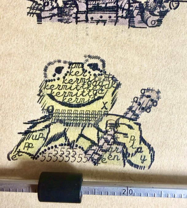 A whimsical, hand-drawn sketch in black ink and yellow color on paper depicting a stitched-together monster-like creature with the word 'kermit' repeated in its face, photographed next to a ruler.