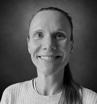A black-and-white portrait shows a smiling woman with her hair pulled back, wearing a light-colored sweater against a dark gradient background. The accompanying post about 2026 being 69% complete suggests this image may be a personal year-end reflection or update, perhaps featuring a team member or the author herself.