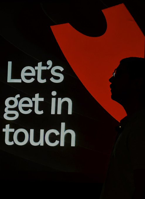 A silhouette of a person standing in front of a screen displaying the text 'Let's get in touch' alongside a red graphic.