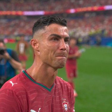 A close-up of Cristiano Ronaldo in a red Portugal national team jersey, appearing emotional after a match.