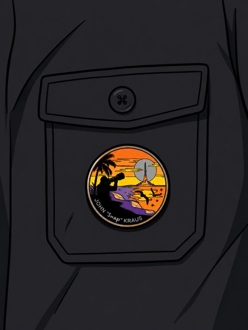 An illustration of a dark shirt pocket featuring a colorful circular pin with a sunset beach scene, a camera silhouette, and the text 'JOHN 'SNAP' KRAUS'.