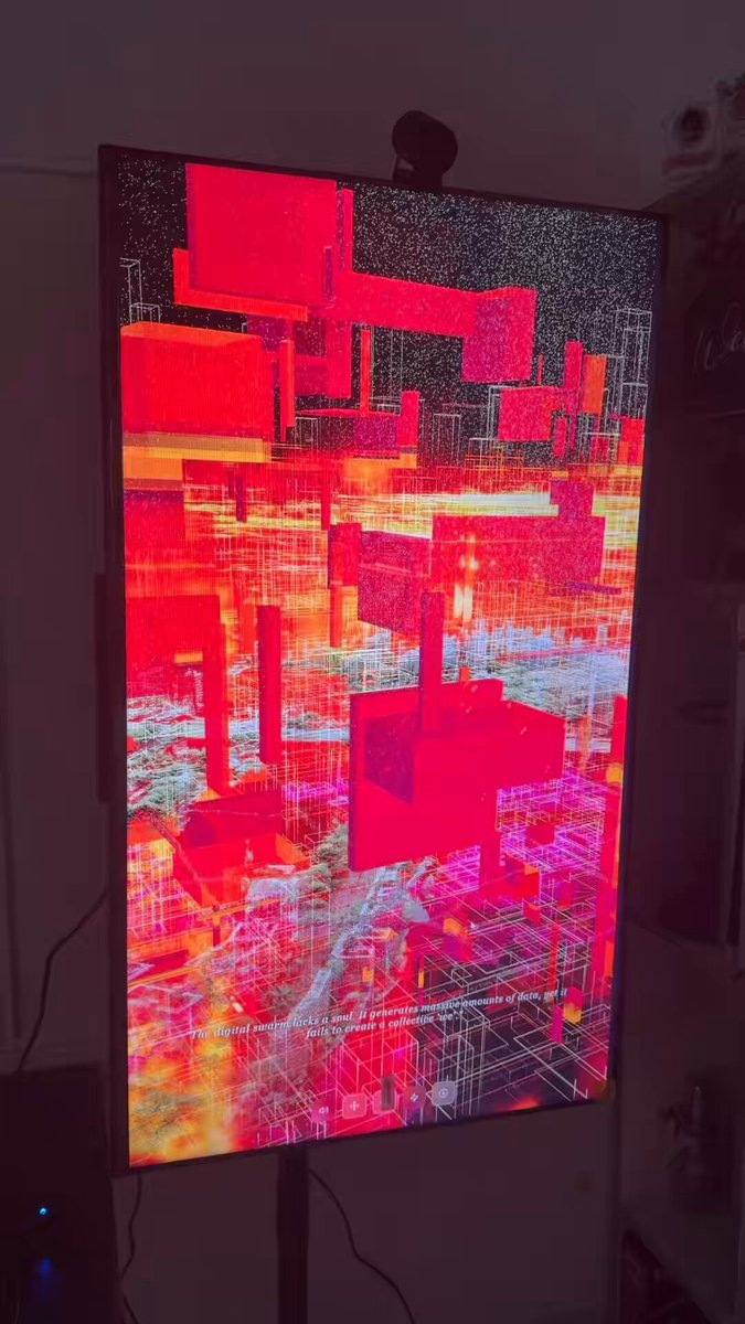 The image features a large, colorful screen with an abstract design that appears to be a cityscape or skyline. The screen has a red background with white lines and shapes, creating a visually striking effect. It seems to be part of a larger display system, as there is also a speaker visible in the scene. The image is accompanied by text that reads "The Fury of City 700 tezitos Interactive piece on Objkt". This suggests that the screen may be part of an interactive art installation or exhibit, possibly related to the theme of urban environments and cityscapes.